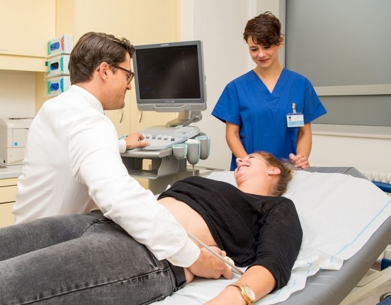 Das Bild zeigt eine Patientin, an der eine Ultraschalluntersuchung durchgeführt wird