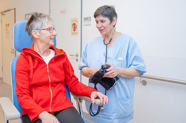 Das Bild zeigt eine Patientin und eine Pflegekraft im Gespräch